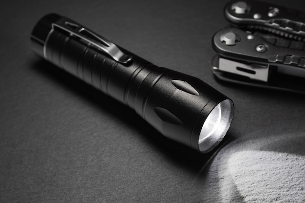 Black flashlight on the stone surface. Tools for work, search and tourism ..