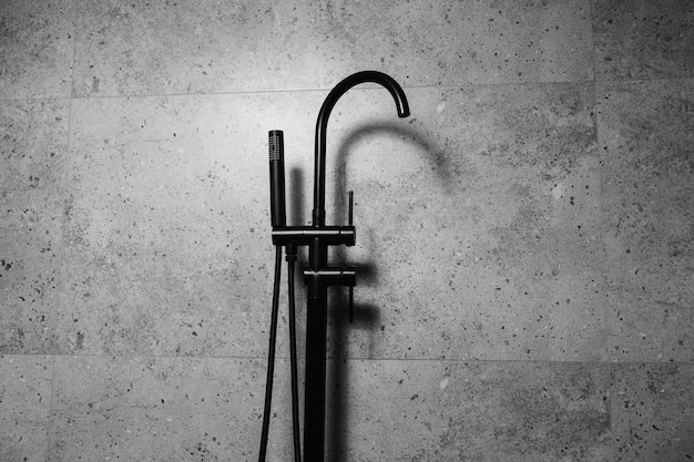 Black floorstanding bath taps on the background of dark grey bathroom walls