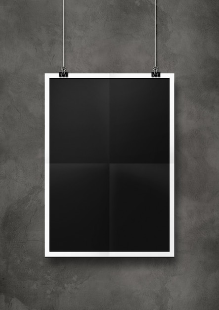 Black folded poster hanging on a concrete wall with clips