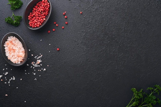 Black food cooking background Stone texture with sea salt pepper garlic and parsley Abstract food background Empty space for text Can be used for food posters design of menu Top view