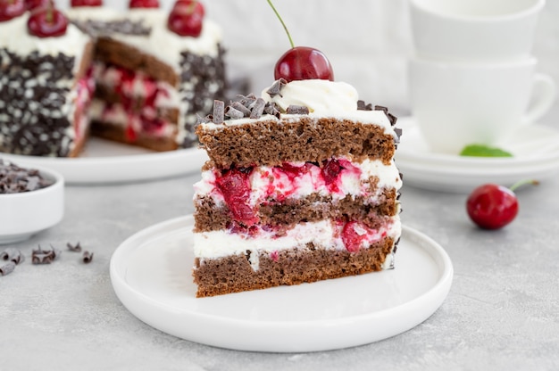 Torta foresta nera, torta schwarzwald. torta al cioccolato fondente, panna montata e ciliegia su fondo grigio cemento. copia spazio.