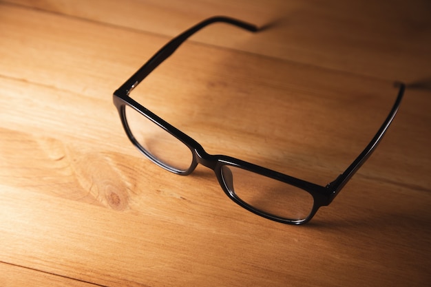 Black frame eye glasses on wooden desk