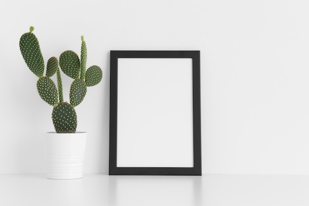Black frame mockup with a opuntia cactus in a pot on a white table Portrait orientation