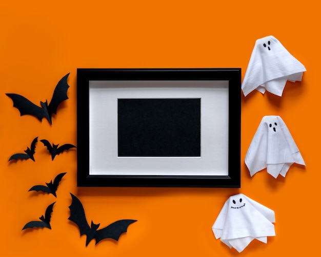  black frame with bats and ghosts on orange background .  Flat lay, top view.