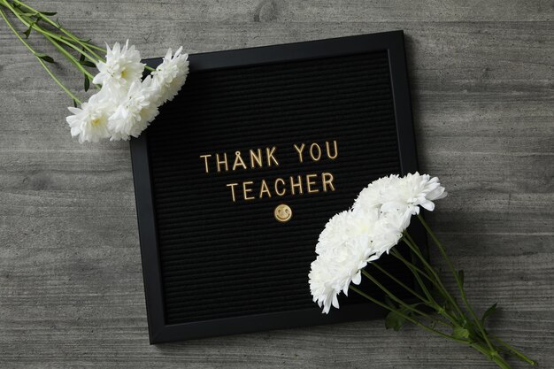 Photo black frame with text and white flowers on wooden background