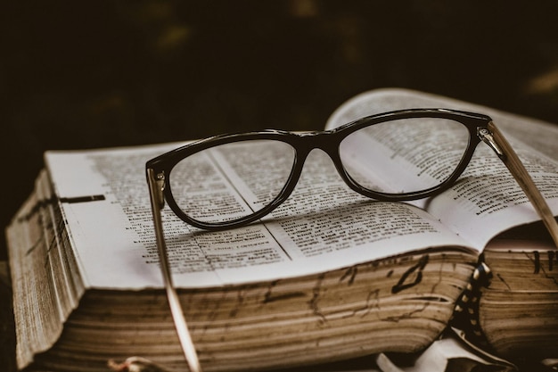 Black Framed Eyeglasses on Top of Open Book Photo