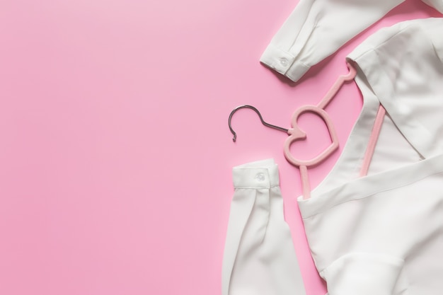Black Friday, clothing industry concept on pink background flat lay with pink clothes hanger and white blouse dress with heart shape on hanger