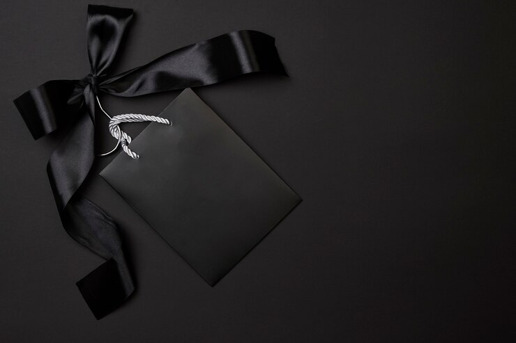 Black friday concept black shopping bag on cloth holder with big black ribbon on dark background