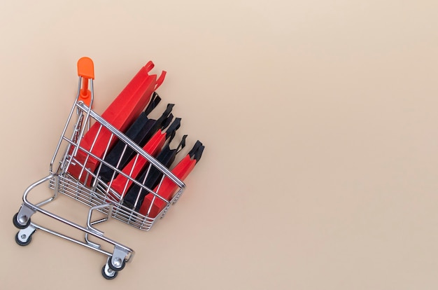 Black friday concept, mockup of paper black and red shopping bags with trolley on colored background. Black Friday sale.