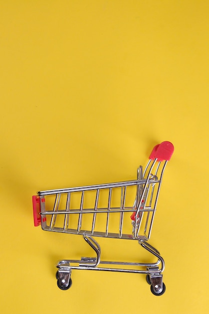 Black Friday. The concept of shopping. sale. Red shopping trolley on a yellow background. view from above