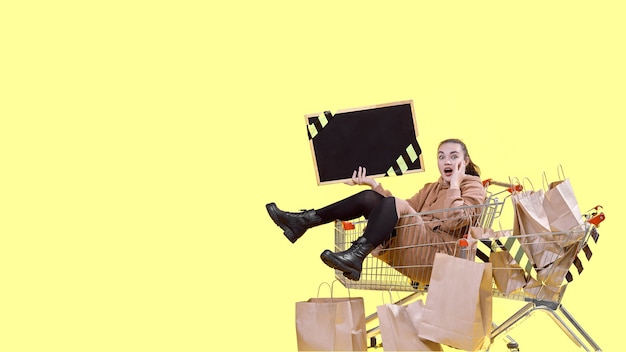 Black Friday, a girl is sitting in a shopping basket with a sign in her hands