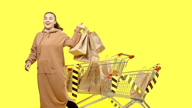 Black Friday, a happy girl holds shopping bags, standing next to shopping carts