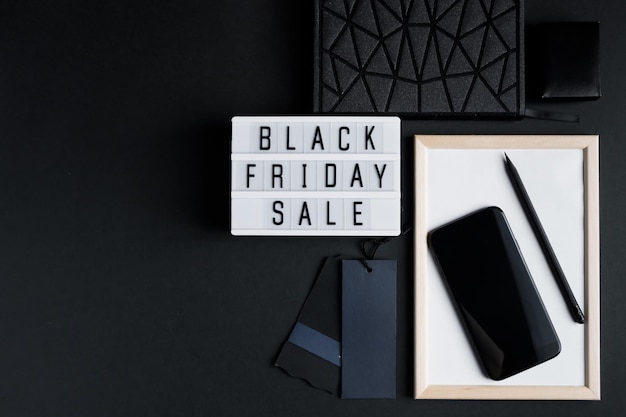 Foto concetto di vendita online del black friday flatlay monocromatico su sfondo scuro smartphone e accessori