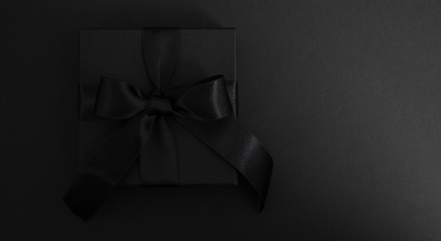 블랙 프라이데이 세일 (Black Friday Sale) 은 블랙  뷰에 고립된 리본 활이 있는 블랙 기프트 박스이다.
