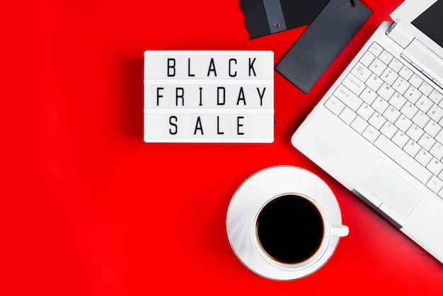 Photo black friday sale concept laptop and coffee cup on red background banner for advertising