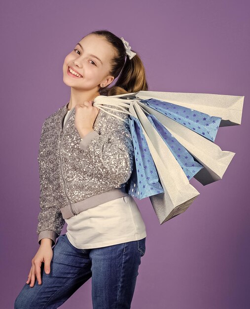 Black friday sale discount shopping day child hold bunch\
packages kids fashion birthday girl favorite brands and hottest\
trends girl with shopping bags violet background shopping and\
purchase