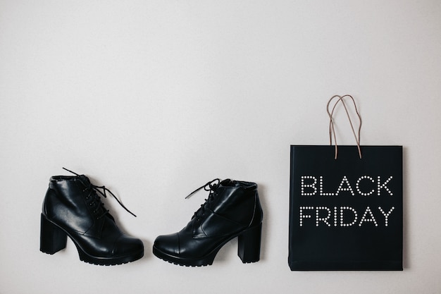 Black friday sale flat lay, Black friday bag and boots on the white wall,
