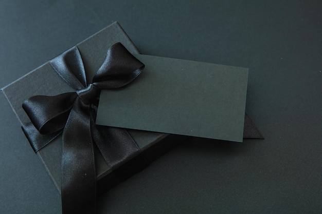 black friday sale gift box with black ribbon and empty card isolated on black
