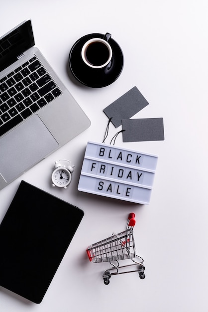 Black Friday Sale words on lightbox with cup of coffee, laptop and clock