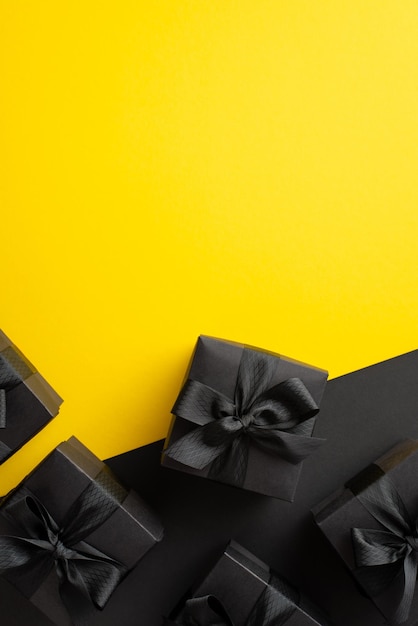 Black friday sales concept top view vertical photo of black gift boxes with ribbon bows on bicolor yellow and black background with copyspace