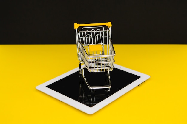 Black friday sales. small shopping trolley on a tablet in yellow background. cybermonday concept