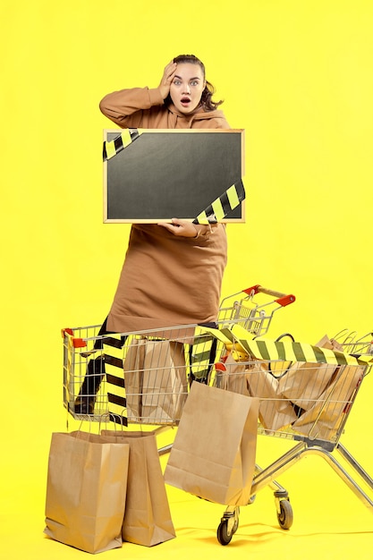 Black Friday. A shocked girl holds a black sign, with a place to copy, in a shopping cart.