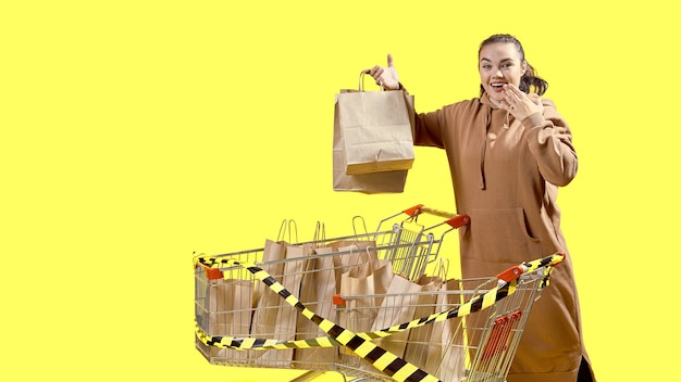 Black Friday, a surprised girl holds shopping bags while standing next to shopping carts