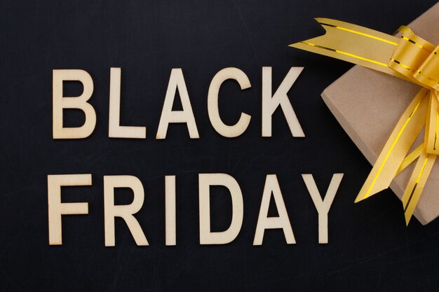 Black Friday - tekst in houten letters op blackboard met cadeau. Ruimte kopiëren.