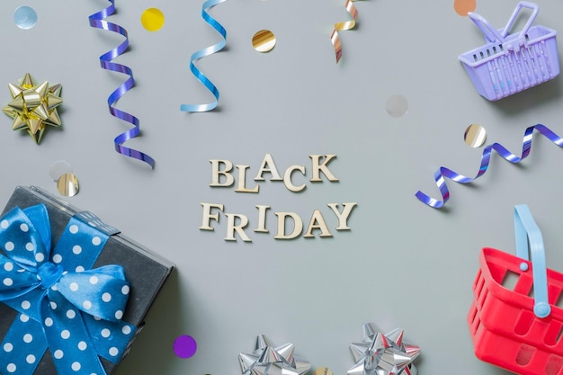 Black friday text with gifts shopping baskets and festive tinsel flat lay