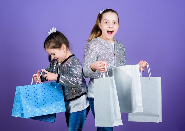 Black friday Verkoop en korting Winkeldag Kinderen bospakketten Kindermode Meisjes zussen vrienden met boodschappentassen violette achtergrond Omdat beeld alles is Winkelen en kopen