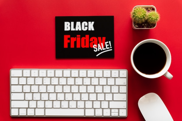 Black friday-verkooptekst op een rood en zwart etiket met koffiekop, toetsenbord op rode achtergrond