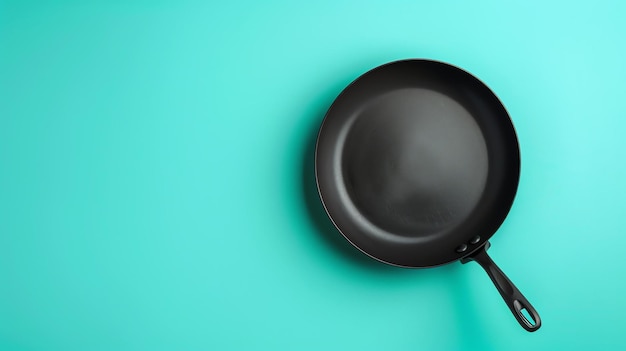Photo black frying pan isolated on blue background top view