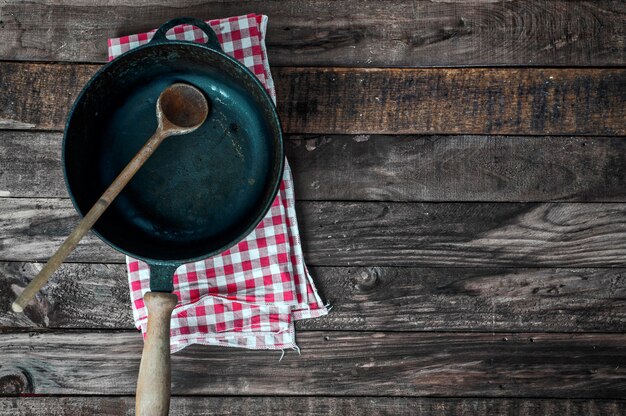 Black frying pan with a wooden spoon on a brown wooden surface