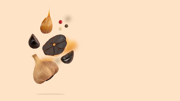 Black garlic bulbs fly in the air on a beige background An image of floating black garlic Concept of vegan and fermented food Selfcare healthy nutrition Copy space Horizontal