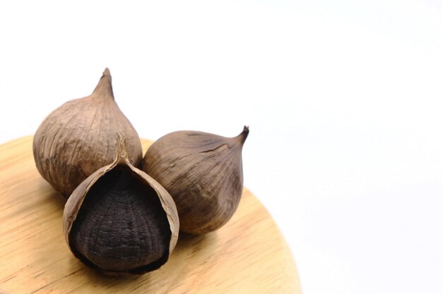 black garlic on wood bowl with white background