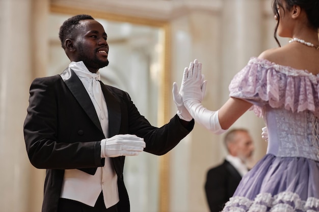 Foto un gentiluomo nero che balla con una signora nella sala da ballo del palazzo