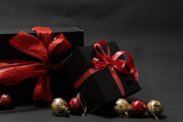 Black gift box, balls, red Christmas decorations on the dark wooden background copy space