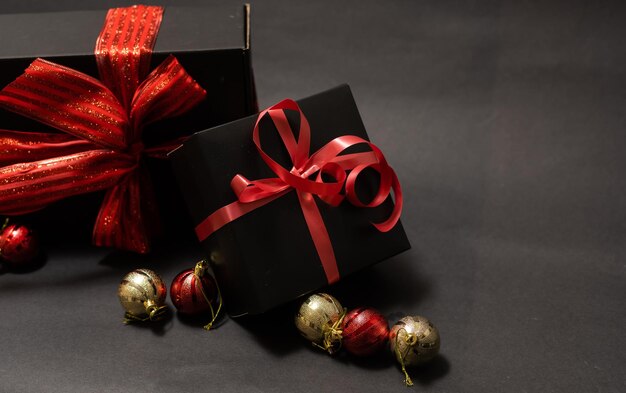 Black gift box, balls, red Christmas decorations on the dark wooden background copy space