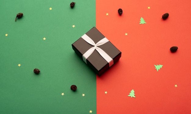 Black gift box on a bright background with stars cones and little Christmas trees