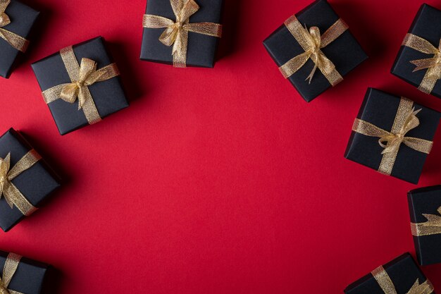 Black gift box with golden ribbons on red paper