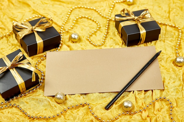 Фото Черные подарочные коробки с золотой лентой и чистым листом бумаги