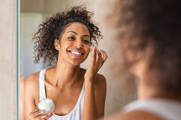 Photo black girl applying lotion on face