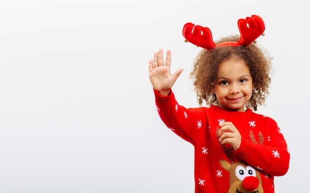 A Black girl in a Christmasthemed reindeer costume makes a welcoming gesture