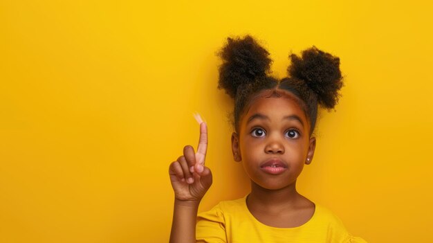 Black girl pointing fingers at copy space over yellow background