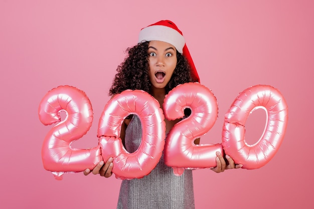 Black girl with holiday balloons wearing santa hat