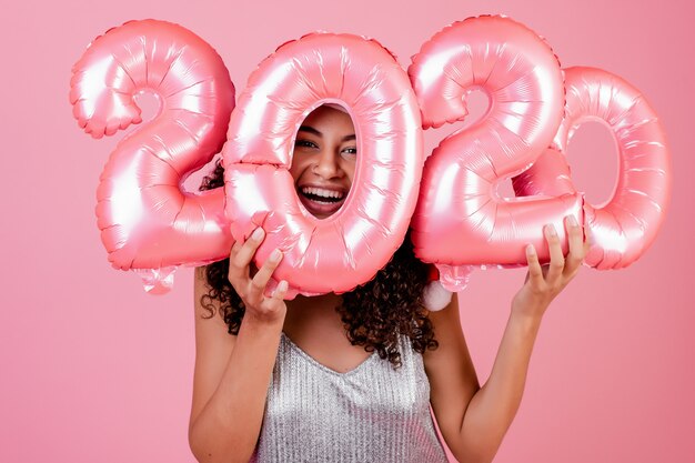 Black girl with holiday balloons wearing santa hat