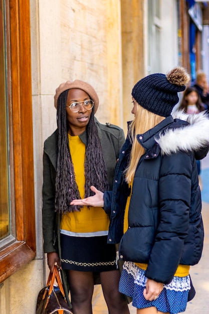 Black girl with a surprised face talking to her blonde friend