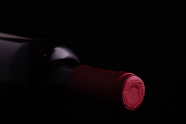 Black glass bottle of red wine on black background