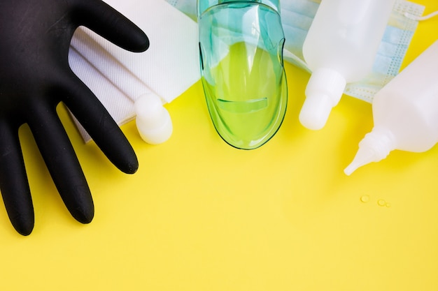 Фото Черная перчатка, защитная маска, антибактериальные дезинфицирующие средства в белых флаконах, бумажные носовые платки
