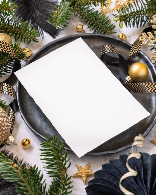 Photo black and golden christmas table setting with ornaments and fir tree branches menu card mockup